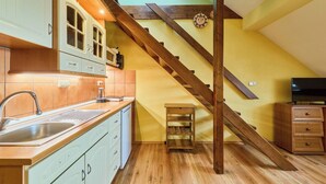 A kitchen with wooden flooring, a wooden staircase, and a small wooden table. - Vysoké nad Jizerou by Interhome (Vysoké nad Jizerou)