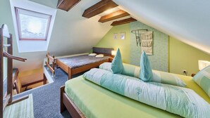 A cozy attic bedroom with a sloped ceiling, a wooden bed, a small desk, and a window with a view. - Vysoké nad Jizerou by Interhome (Vysoké nad Jizerou)