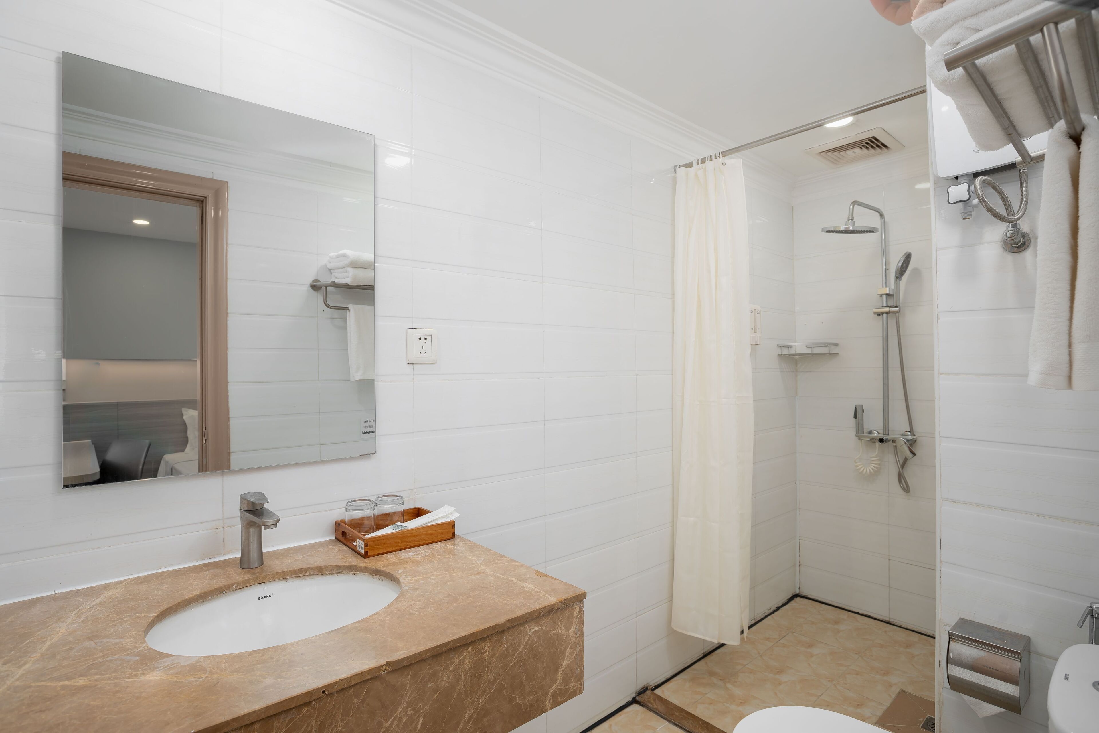 A bathroom with a sink, mirror, shower, and toilet.