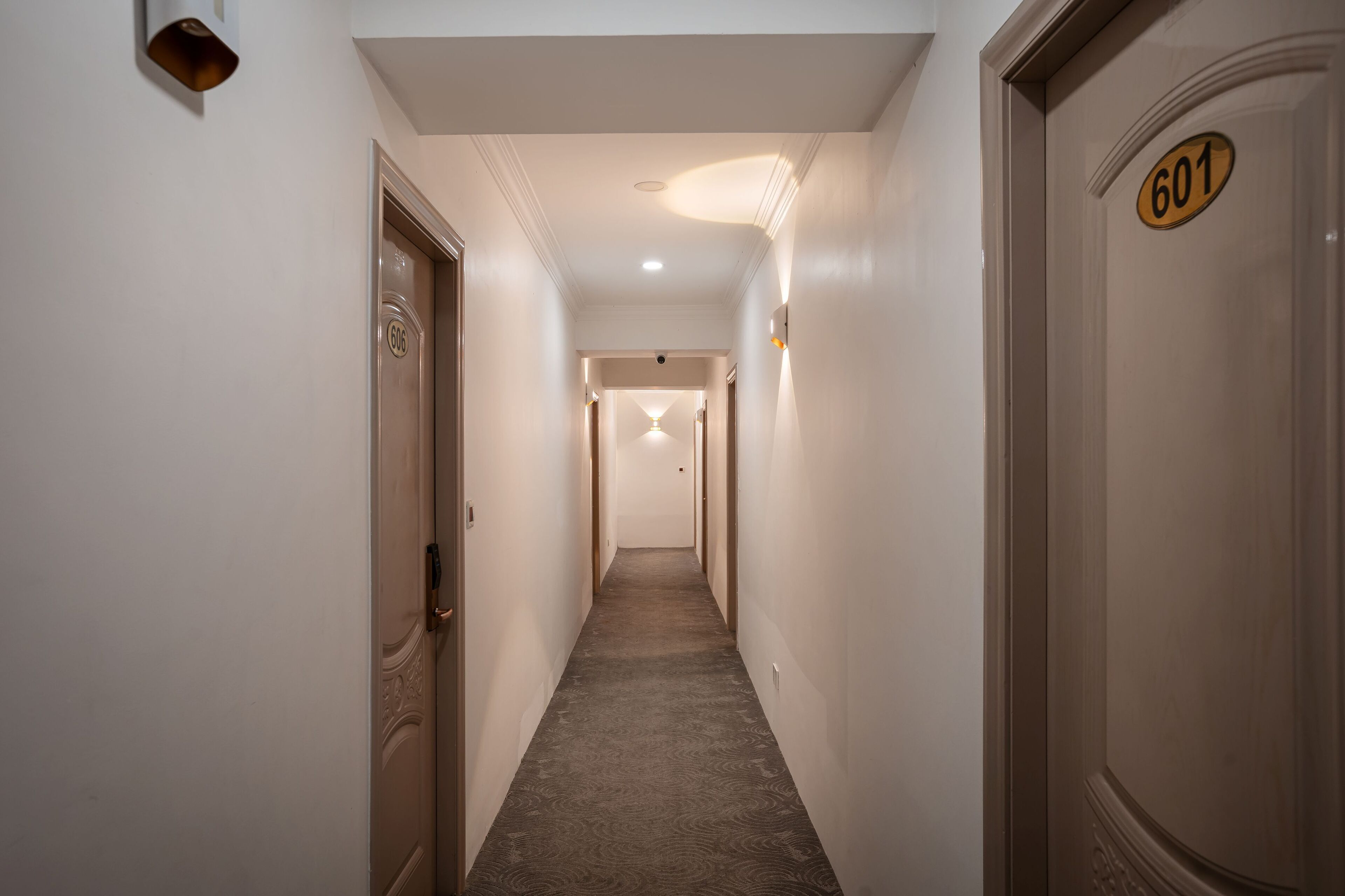 A narrow hallway with a carpeted floor, white walls, and doors numbered 601 and 602.