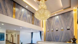 A hotel lobby with a marble reception desk, a chandelier, and clocks on the wall. - Green Star Hotel Yangon (Yangon)