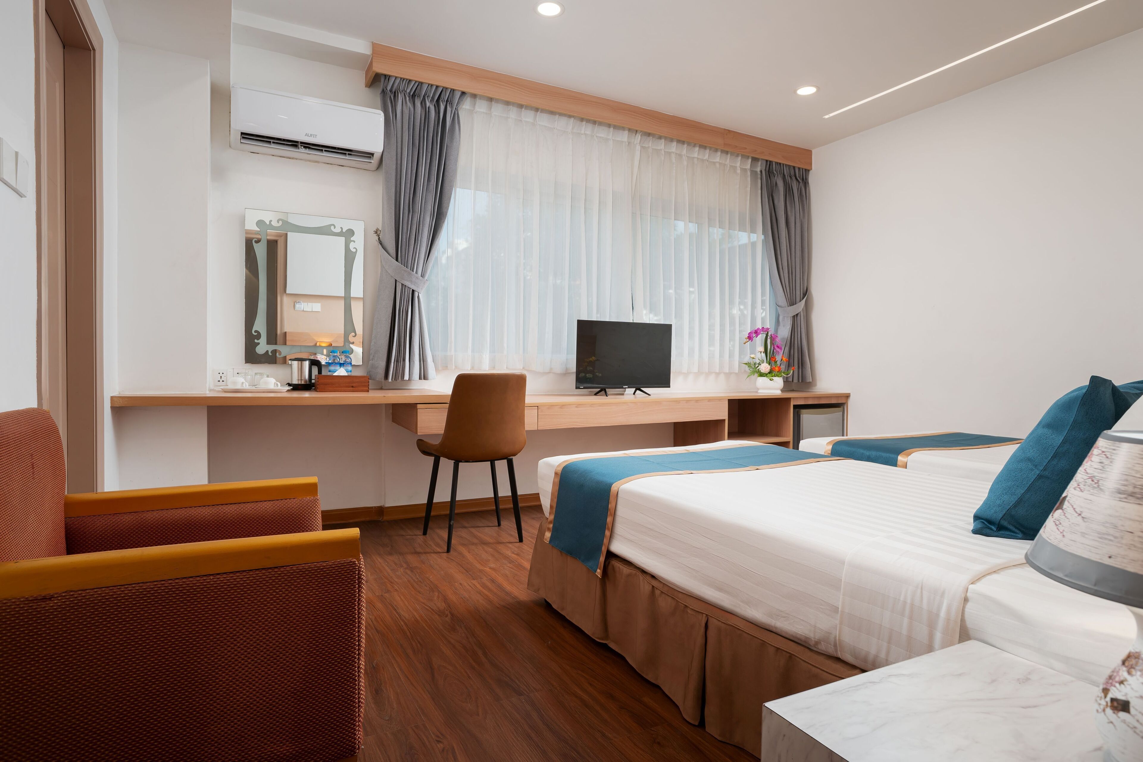 A hotel room with a bed, a desk with a computer, a chair, and a TV.