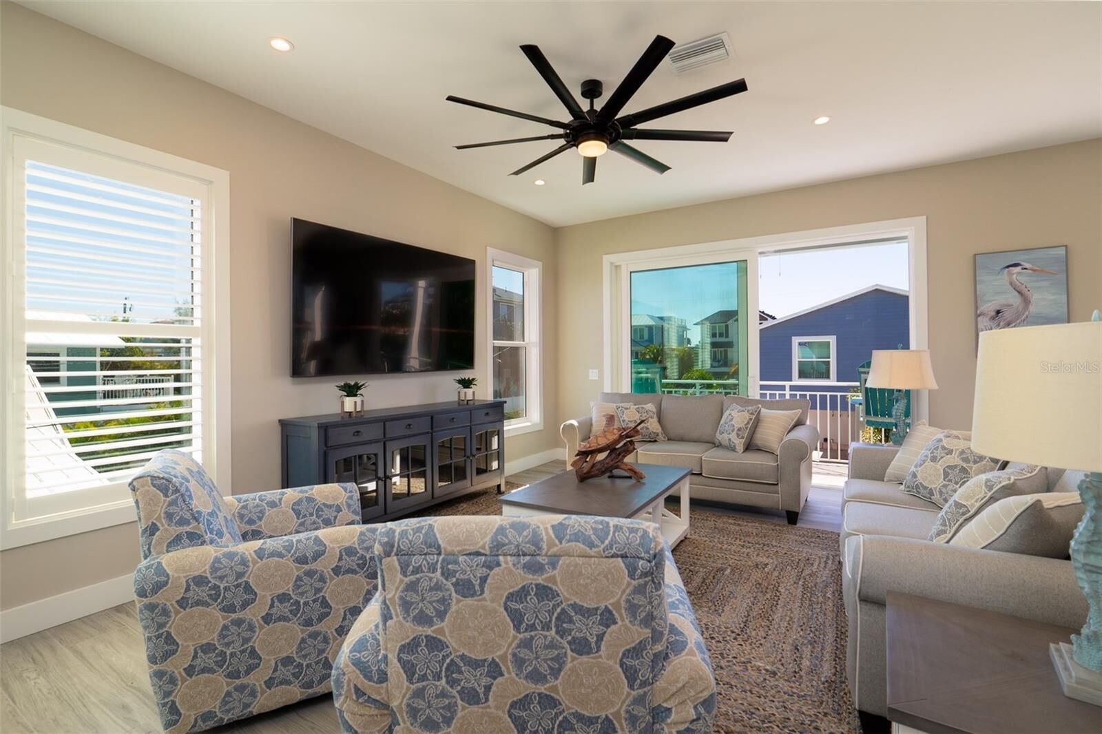 A spacious living room with a modern ceiling fan, a large flat-screen TV, and a comfortable seating area with two sofas and a coffee table.
