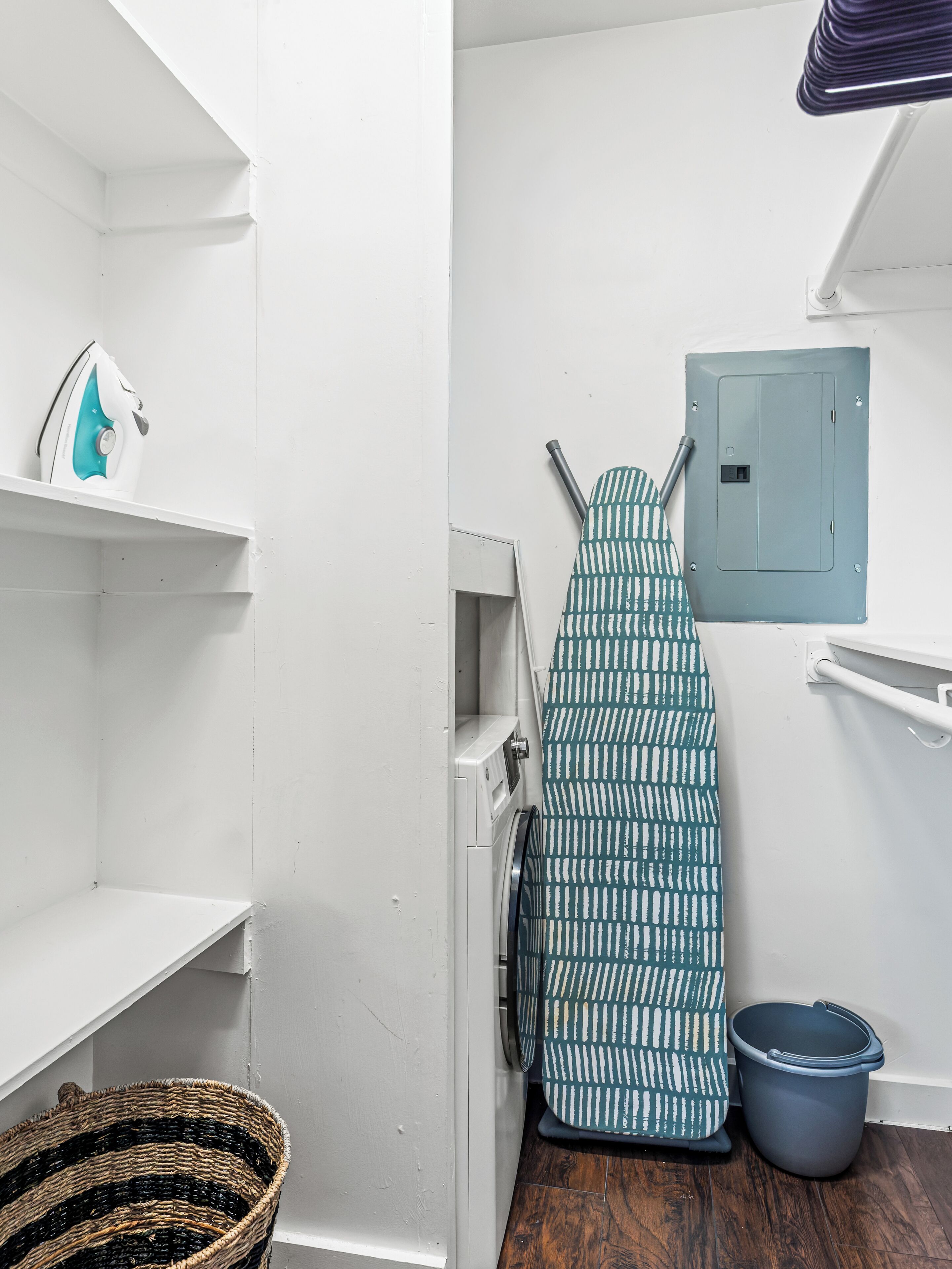 A laundry area with a washing machine, an iron, a drying rack, and a laundry basket.