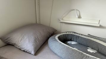 Una habitació amb un llit, un almoiner, una taula de nit i una prestatgeria penjada a la paret.