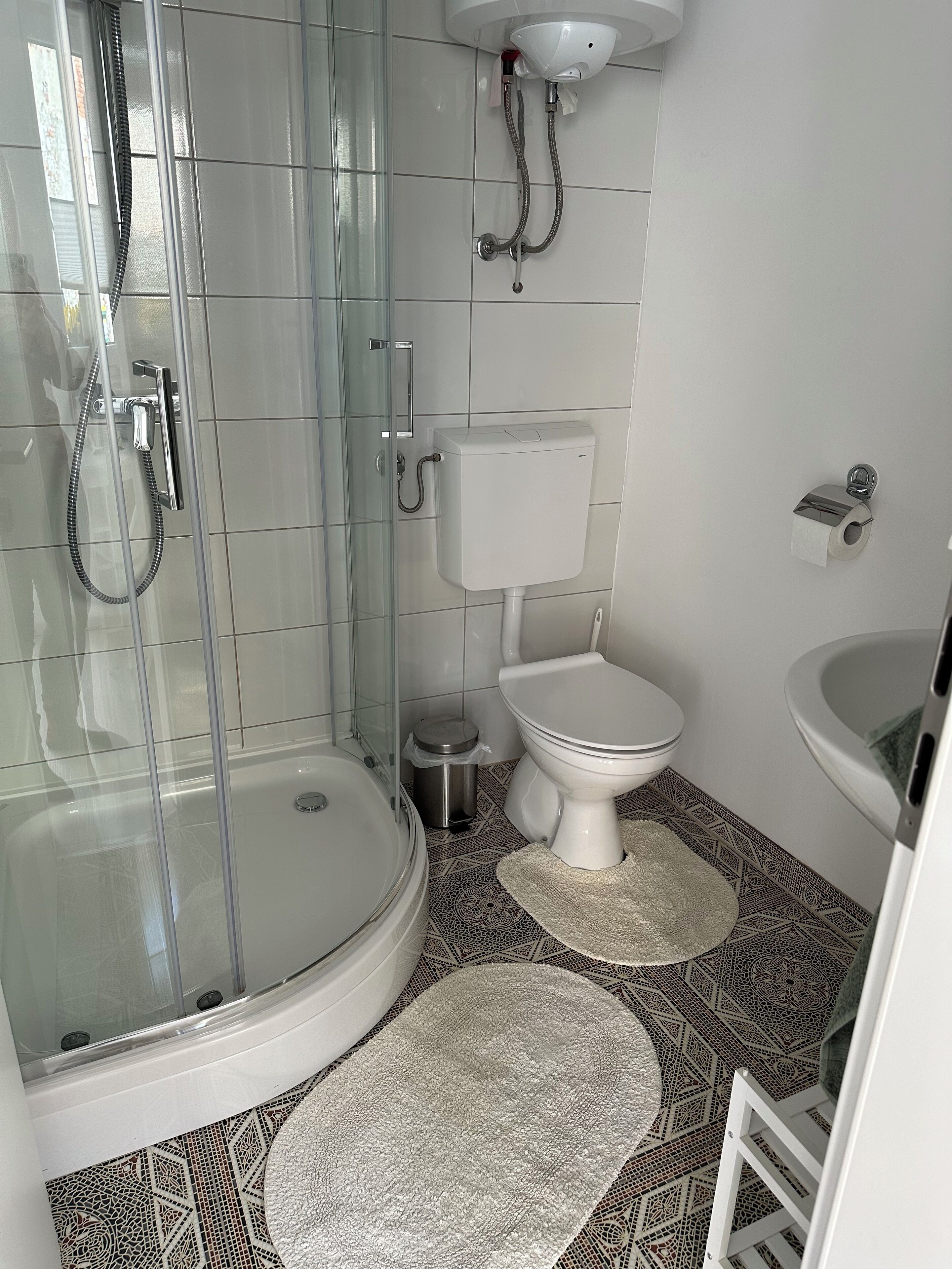 Een badkamer met een douche met glazen wand, toilet en wastafel.