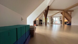Un loft spacieux avec de hauts plafonds, des poutres apparentes et une vue sur l’extérieur grâce à de grandes fenêtres.