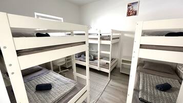 Quarto com beliche, chão claro, tapete pequeno e um quadro na parede.