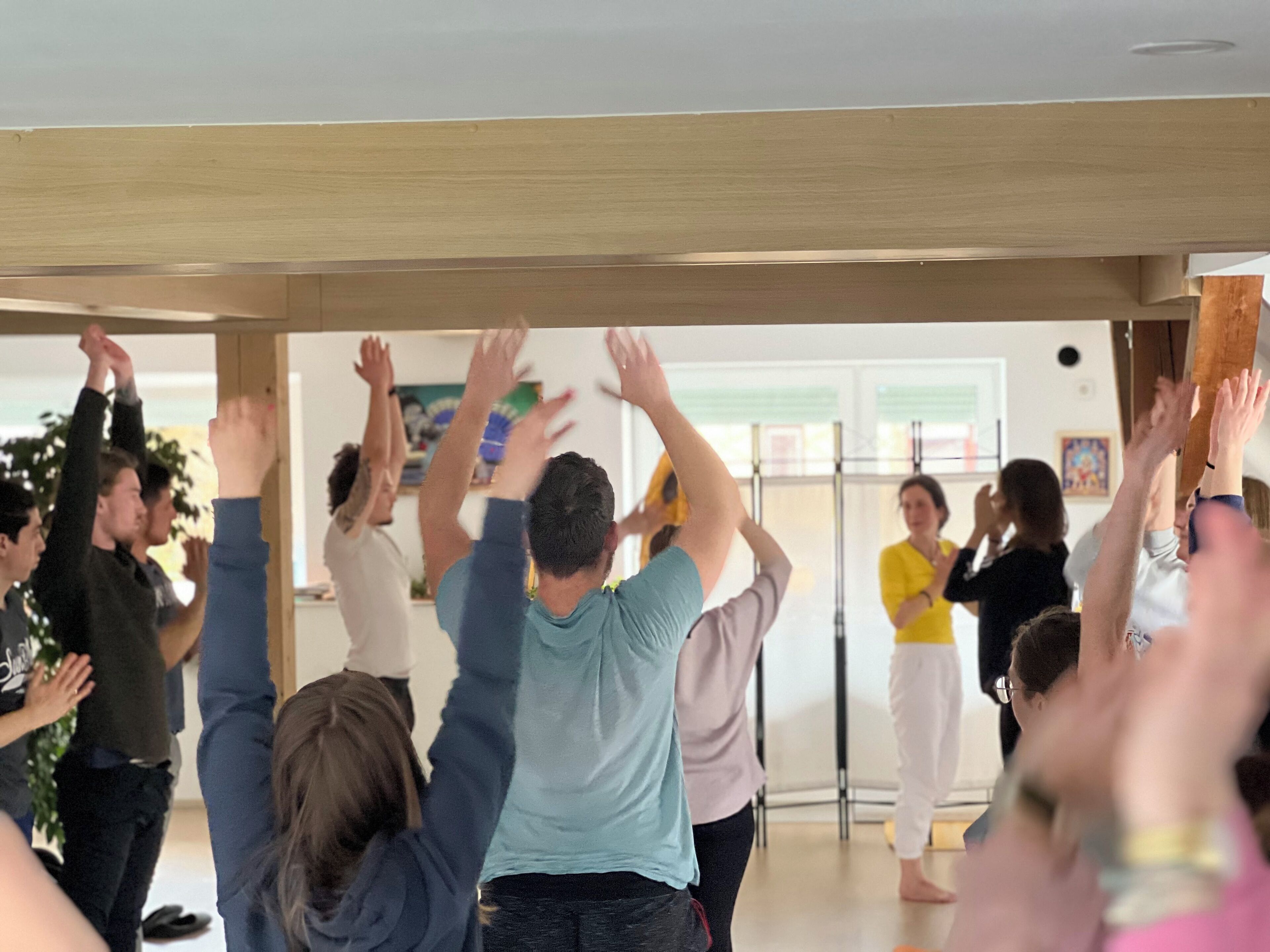Un grupo de personas en una habitación con vigas de madera en el techo, realizando una actividad física o ejercicio.