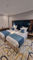 Habitación de hotel con dos camas, un escritorio, un teléfono y una alfombra estampada.