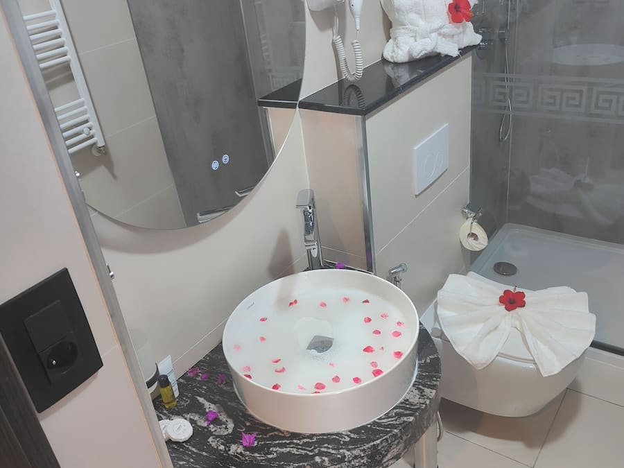 Un baño con un lavabo redondo, un espejo, toallero, ducha e inodoro.