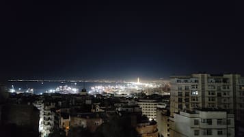 Un paisaje urbano nocturno con edificios iluminados y una vista distante del horizonte de la ciudad.