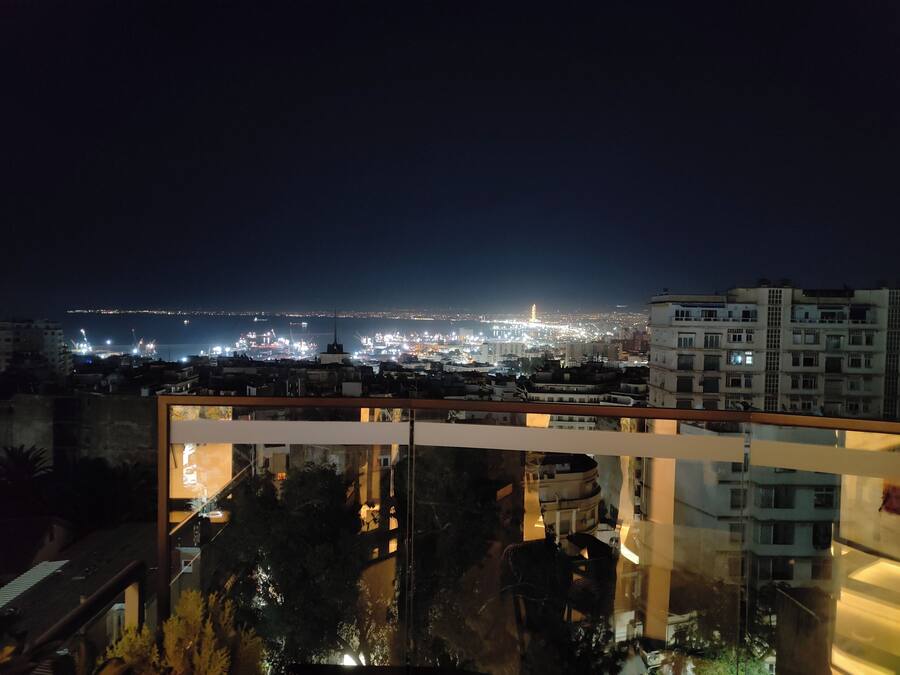 A nighttime cityscape with a view of a distant city and a modern building with a balcony.