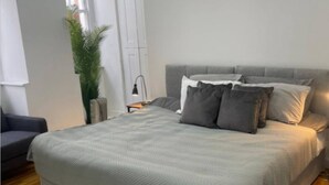 Ein Schlafzimmer mit einem großen Bett, einem Nachttisch, einer Lampe und einer Topfpflanze.