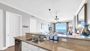 A kitchen with granite countertops, stainless steel appliances, and a view of the balcony. - 🌅Endless Gulf Views | Pool | Fab Amenities | Ocean Reef 2203🌅 (Panama City Beach)