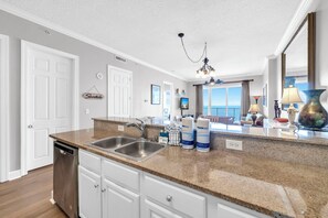 A kitchen with granite countertops, stainless steel appliances, and a view of the balcony. - 🌅Endless Gulf Views | Pool | Fab Amenities | Ocean Reef 2203🌅 (Panama City Beach)