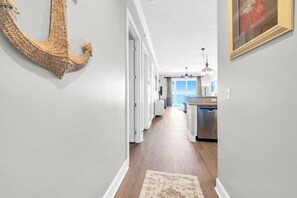 A hallway with a wooden floor, white walls, and a large decorative anchor on the left. - 🌅Endless Gulf Views | Pool | Fab Amenities | Ocean Reef 2203🌅 (Panama City Beach)