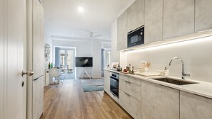 Cozinha moderna com micro-ondas embutido, pia e bancada com diversos objetos.