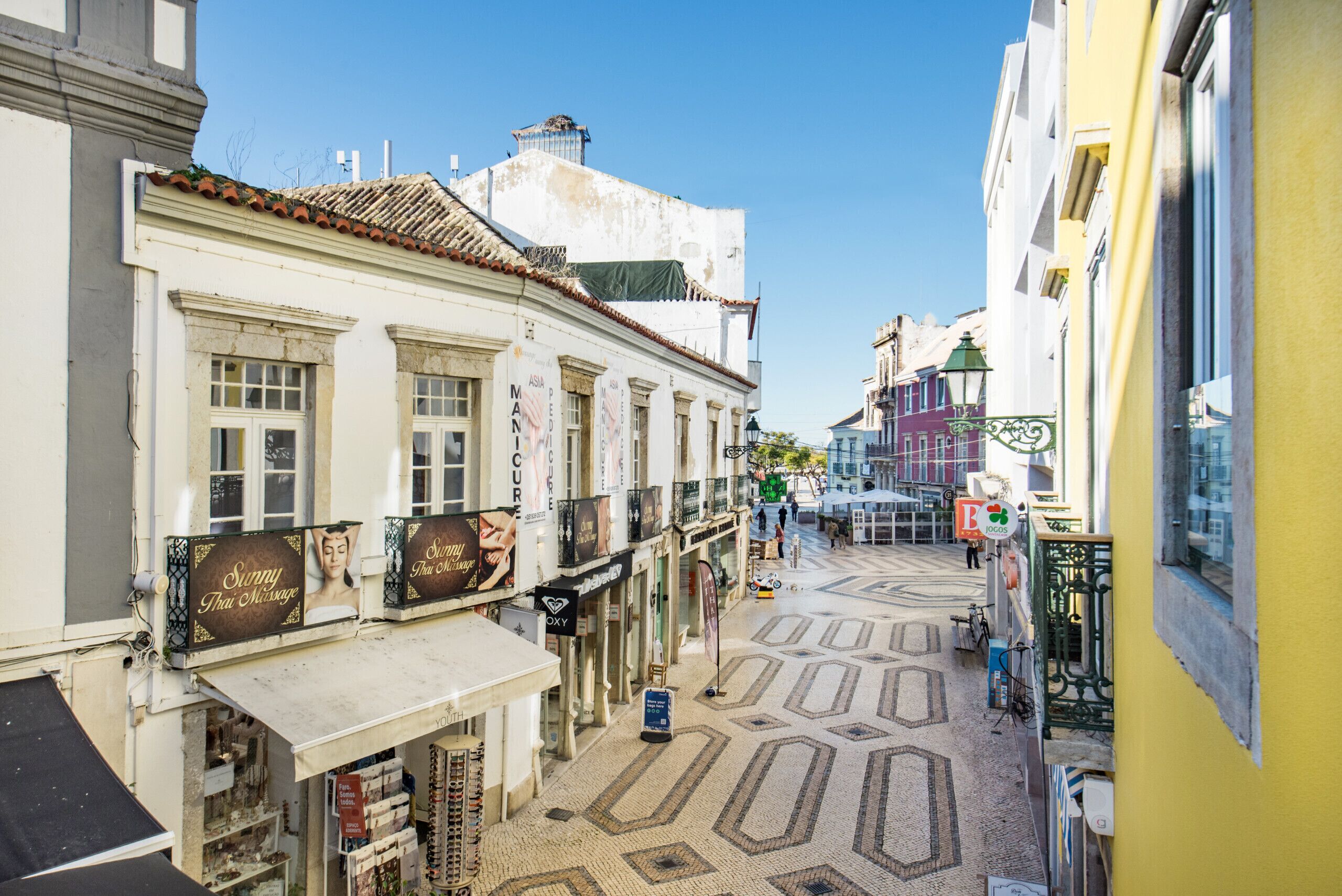 Una calle estrecha flanqueada por edificios, algunos con letreros de tiendas y restaurantes.