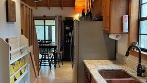 Une cuisine dotée de meubles en bois, d’un plan de travail en granit, d’un réfrigérateur et d’un coin repas avec une table et des chaises.