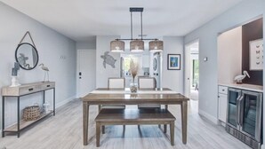 Une cuisine moderne dotée d’un four encastré, d’un coin repas avec une table et un banc en bois, et d’un luminaire suspendu.