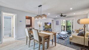 Un salon moderne comprenant un coin repas, un canapé, une table basse et un téléviseur.