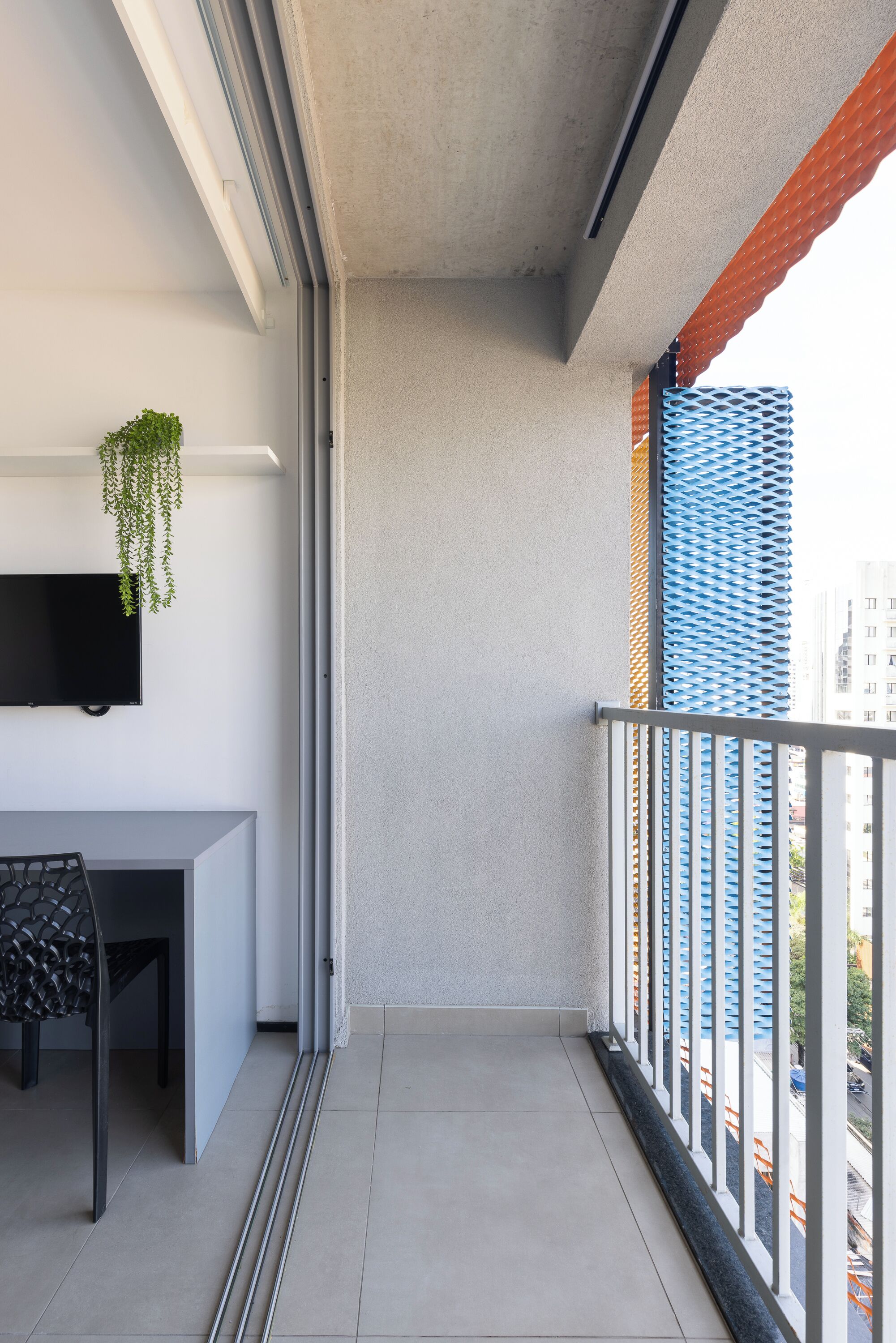 A balcony with a TV, a plant, and a view of the city.