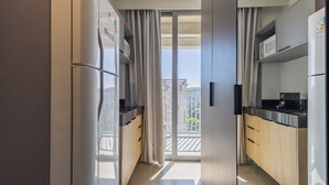 Una cucina moderna con una porta vetrata scorrevole che dà su un balcone, elettrodomestici integrati e pensili in legno.