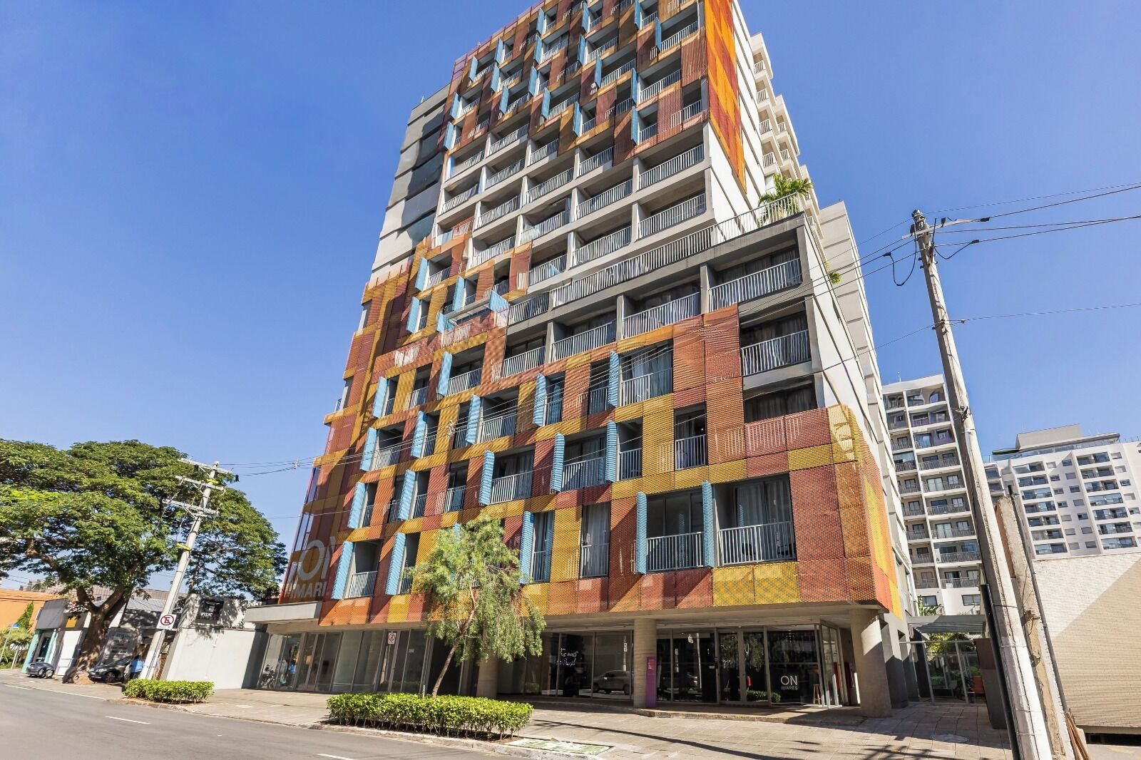 A multi-story hotel with balconies, a ground-level entrance, and a clear sky.