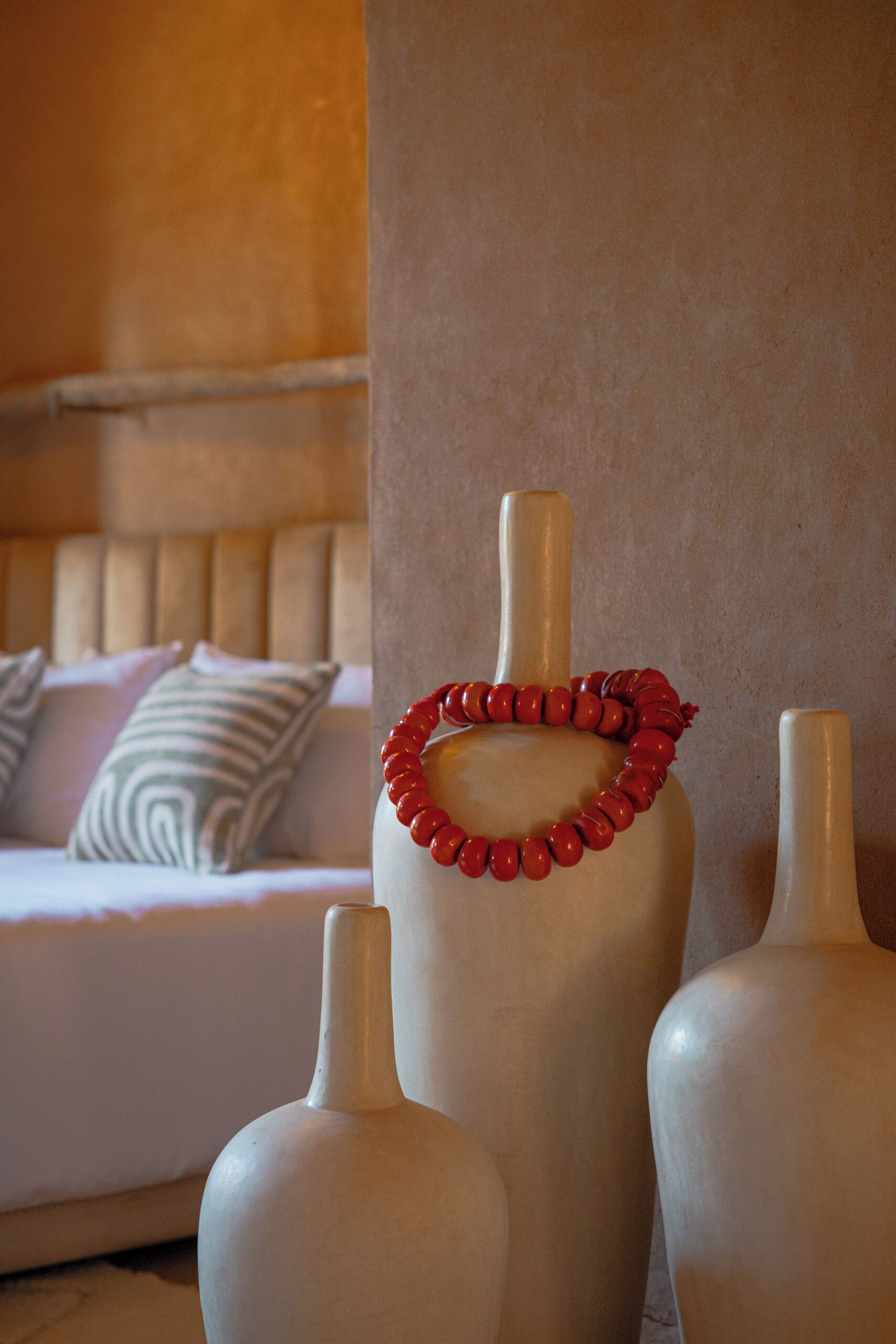 A room with a bed, pillows, and two vases.
