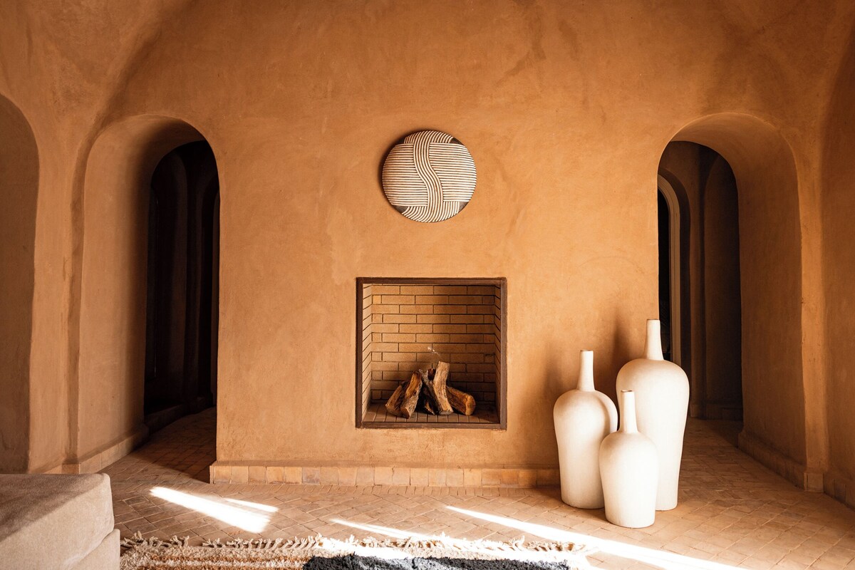 A room with a brick fireplace, large vases, and arched doorways.