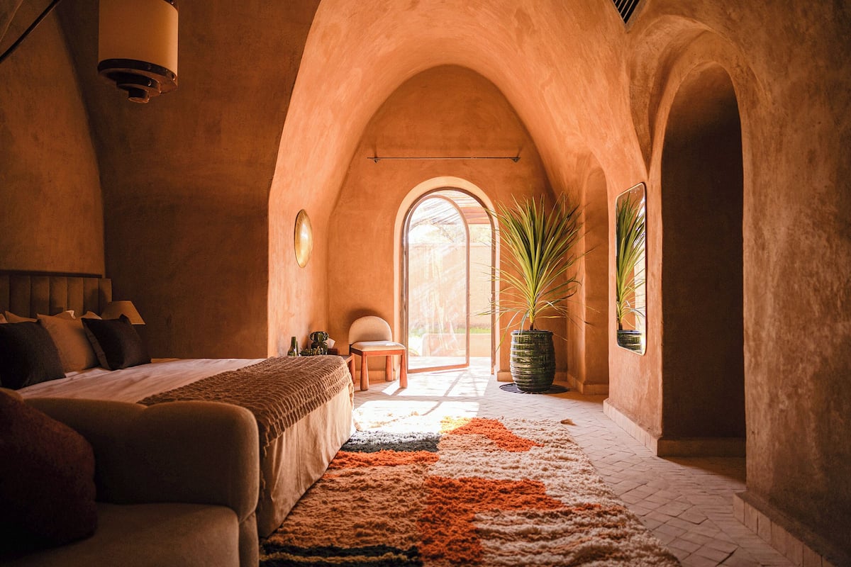 Un dormitorio acogedor con cama, un sofá, un ventanal grande y una planta en maceta.