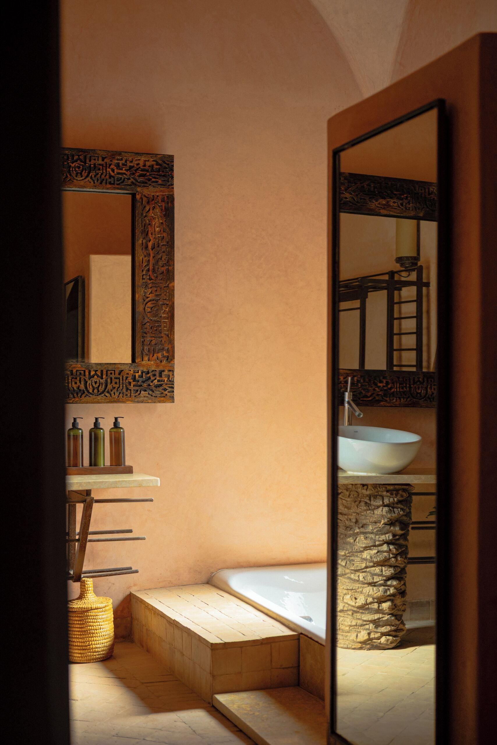 Un baño con lavamanos de piedra, un espejo grande y una bañera.