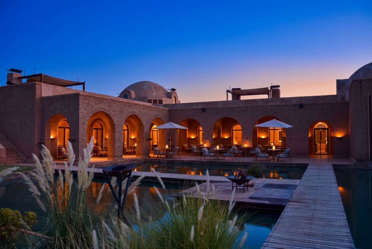 A resort with a pool, outdoor seating, and arched walkways.