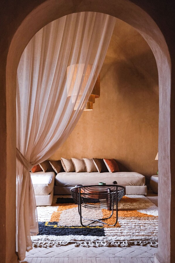 Un dormitorio acogedor con cama, almohadas, una silla y un tapete estampado.