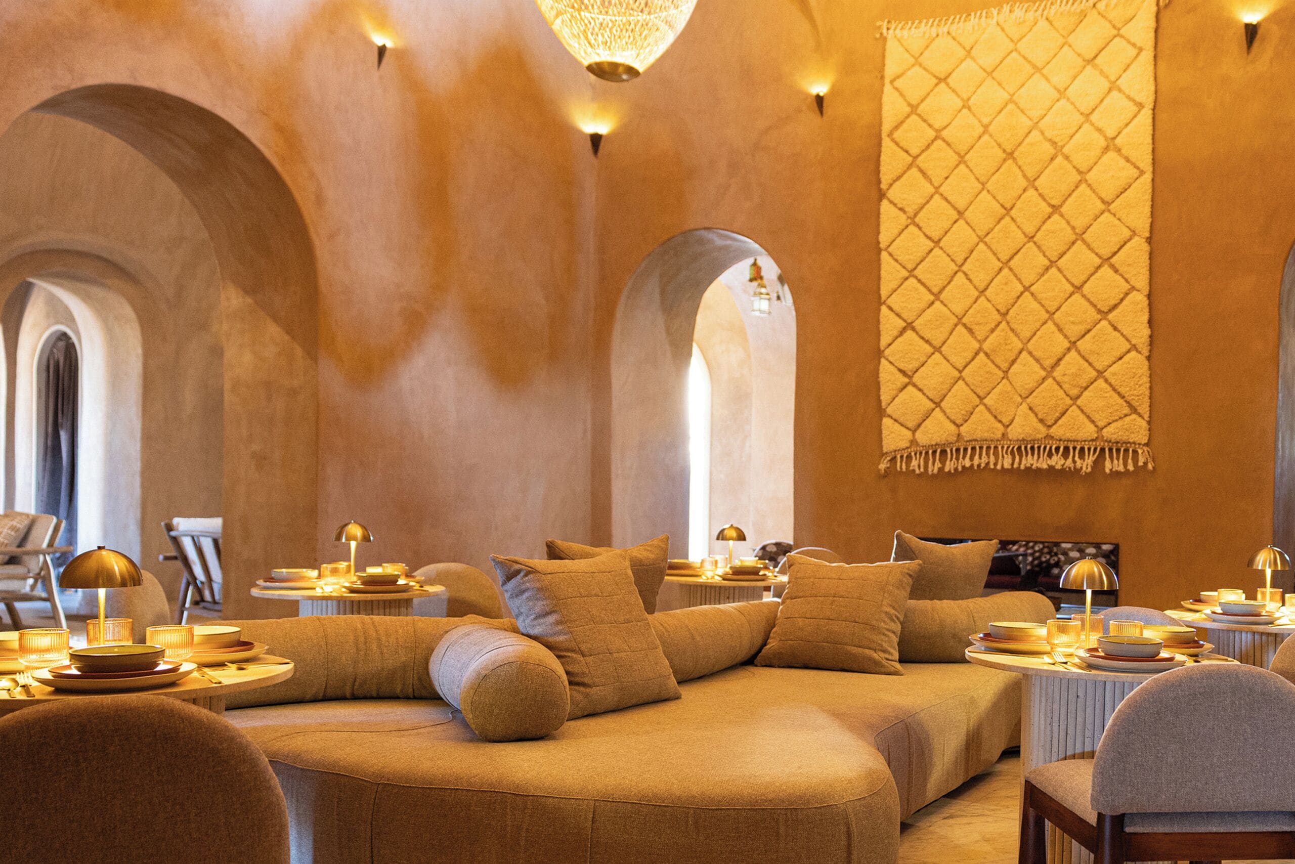 Un intérieur chaleureux et bien éclairé, avec un ensemble de canapés, des tables ornées de bougies et une grande décoration murale.