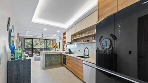 A modern kitchen with a large black refrigerator, wooden cabinets, and a central island. - Northside Retreat - Infinity pool - Fast Wi-Fi (Sayulita)