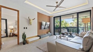 A modern living room with a sofa, coffee table, TV, and a ceiling fan. - Northside Retreat - Infinity pool - Fast Wi-Fi (Sayulita)