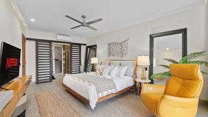 A modern hotel room with a bed, a TV, a ceiling fan, a yellow armchair, and a large mirror. - Northside Retreat - Infinity pool - Fast Wi-Fi (Sayulita)