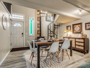 A dining area with a wooden table, white chairs, a spiral staircase, and a decorative lamp. - Historic, 3-Bedroom 1920’s Home on Route 66 (Tulsa)