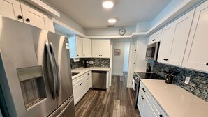 Una cocina moderna con electrodomésticos de acero inoxidable, armarios blancos y salpicadero de azulejos.