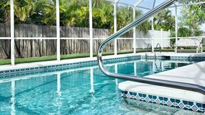Una piscina cristalina con un deck blanco y una barandilla de metal.