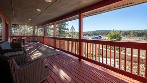 A covered porch with wicker furniture and a view of a forested area. - Enjoy private luxury at Pagosa Valley Views! (Pagosa Springs)