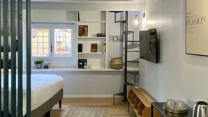Ein modernes Schlafzimmer mit Bett, Bücherregal, Schreibtisch und Couchtisch.