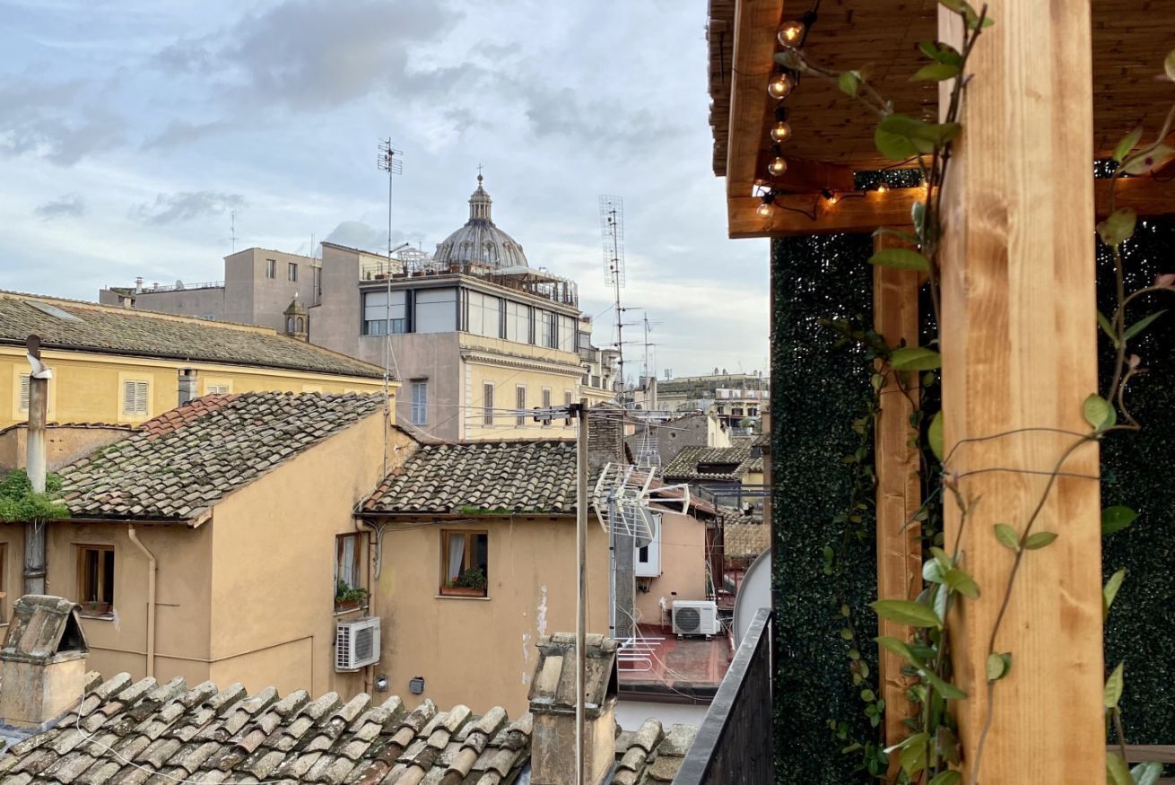 A view of terracotta-tiled rooftops and a building with a dome.