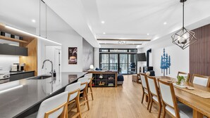 Una cocina moderna con una isla central, sillas de madera y una mesa de comedor con sillas.