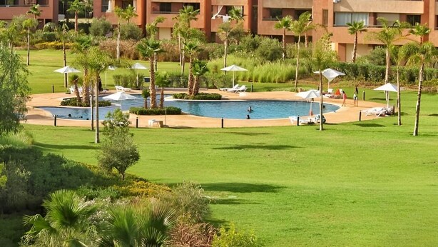 A resort with multiple buildings, a swimming pool, and palm trees. - Luxueux Appartement Prestigia Agate (Marrakech)