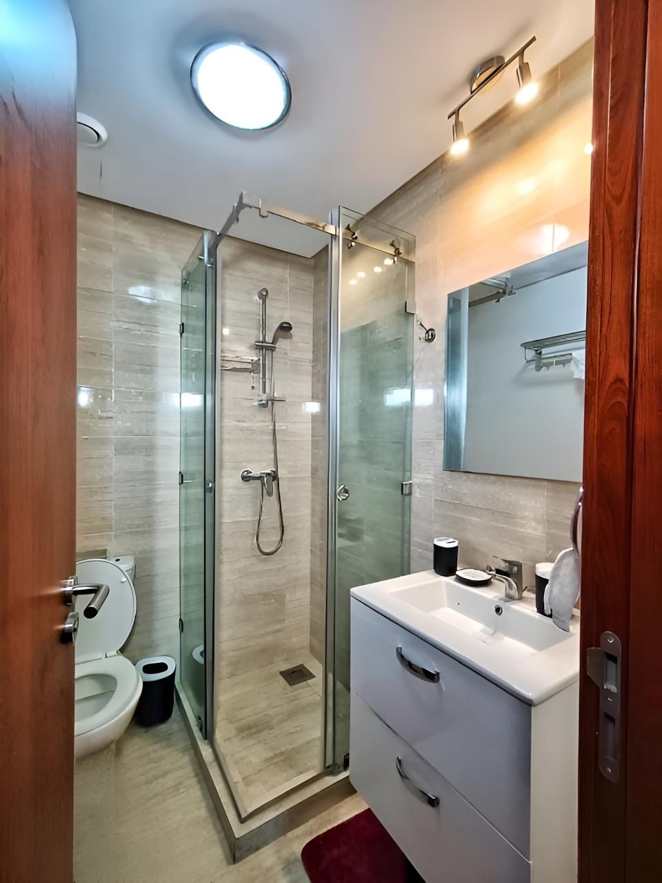Ein modernes Badezimmer mit einer gläsernen Duschkabine, einem weißen Waschbecken und einer Toilette.