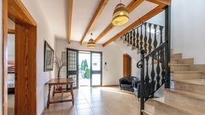Un espacio habitable amplio con escaleras, vigas de madera y vista a través de un ventanal.