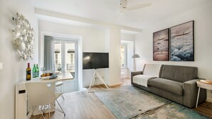 Ein modernes Wohnzimmer mit grauem Sofa, Flachbildfernseher und Kunstwerken an der Wand.
